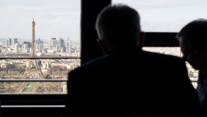 eiffel tower and la defense seen from montparnasse tower while two silhouettes eat