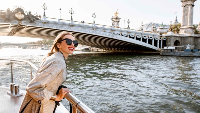 Young woman enjoying beautiful landscape view on the riverside from the tourist ship during the sunset in Paris